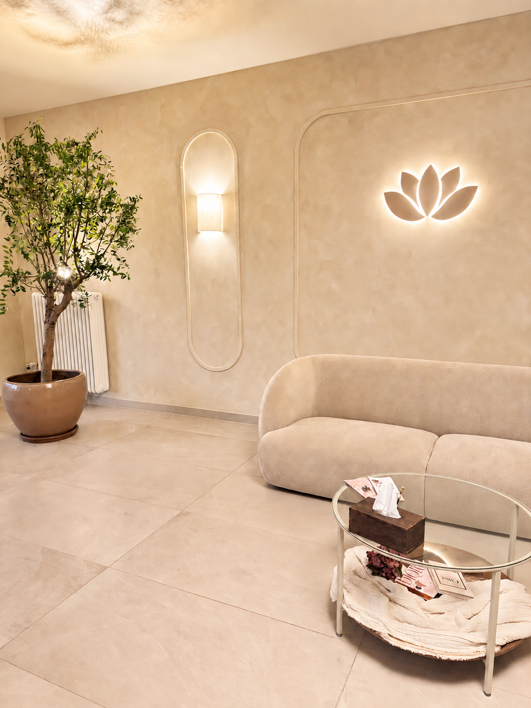 Gemütlicher Sitzbereich bei SIRIN COSMETICS mit beigem Sofa, Glastisch und beleuchtetem Lotus